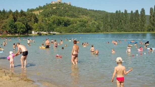 Un llac concorregut amb persones nedant i passejant per l'aigua.