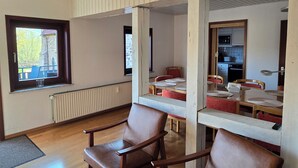 A room with a wooden floor, a window with a view, a radiator, and a dining table with chairs.