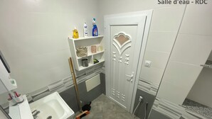 A bathroom with a sink, toilet, shower, and a shelf with toiletries. - Maison Individuelle - Ait Chafaa Azeffoun (Aït Chafâa)