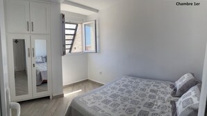 A bedroom with a bed, wardrobe, and a window with a view.