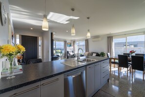 Eine moderne Küche mit Granit Arbeitsplatte, Edelstahlgeräten und Pendelleuchten.