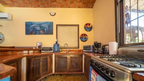 A kitchen with wooden cabinets, a stove, a microwave, and a sink. - Casa Happy Sol - Delfin (San Francisco)