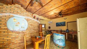 A kitchen with a brick wall, wooden table, chairs, a fish tank, and a refrigerator. - Casa Happy Sol - Delfin (San Francisco)