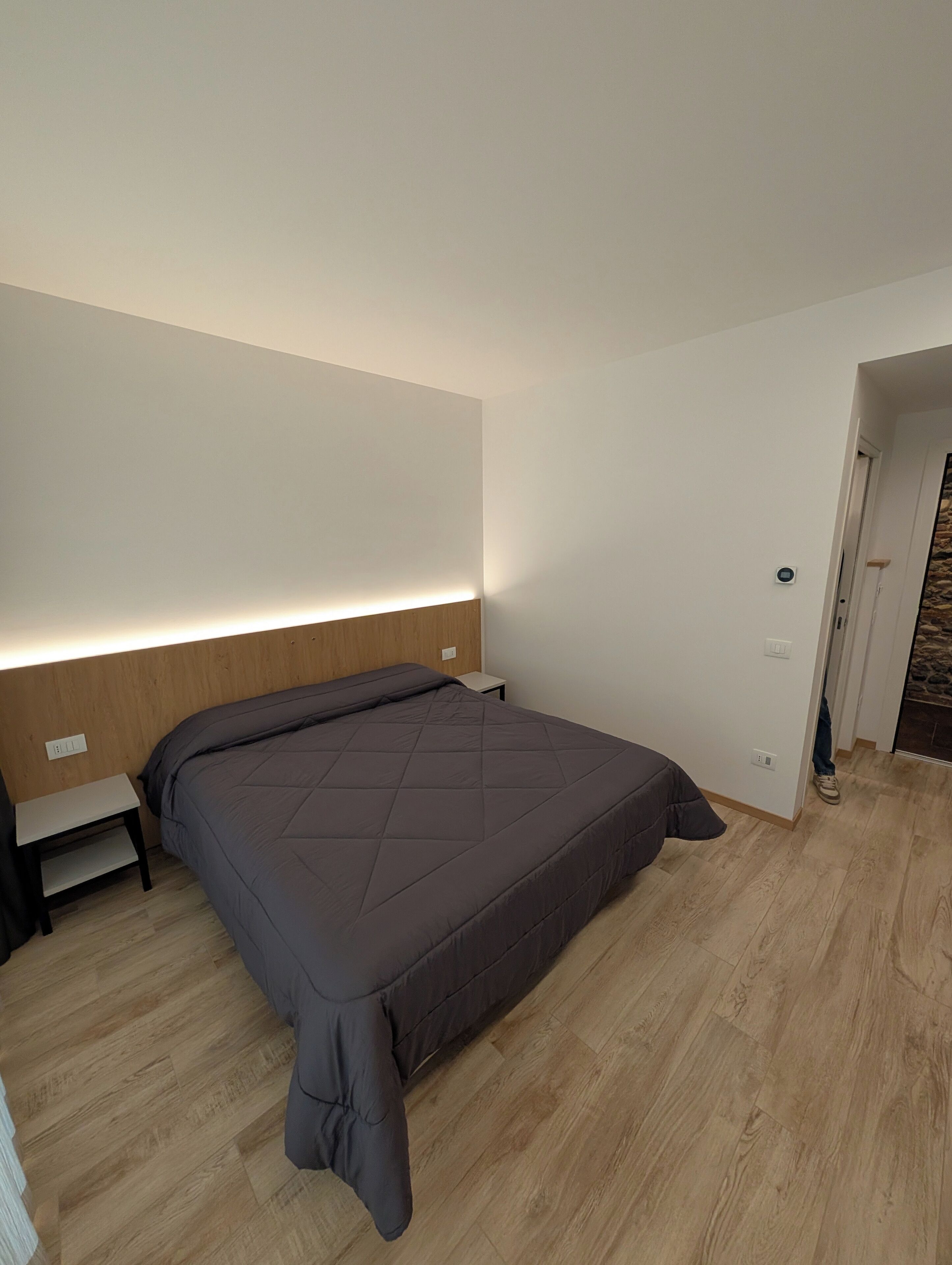 A modern bedroom with a large bed, a bedside table, and a nightstand.