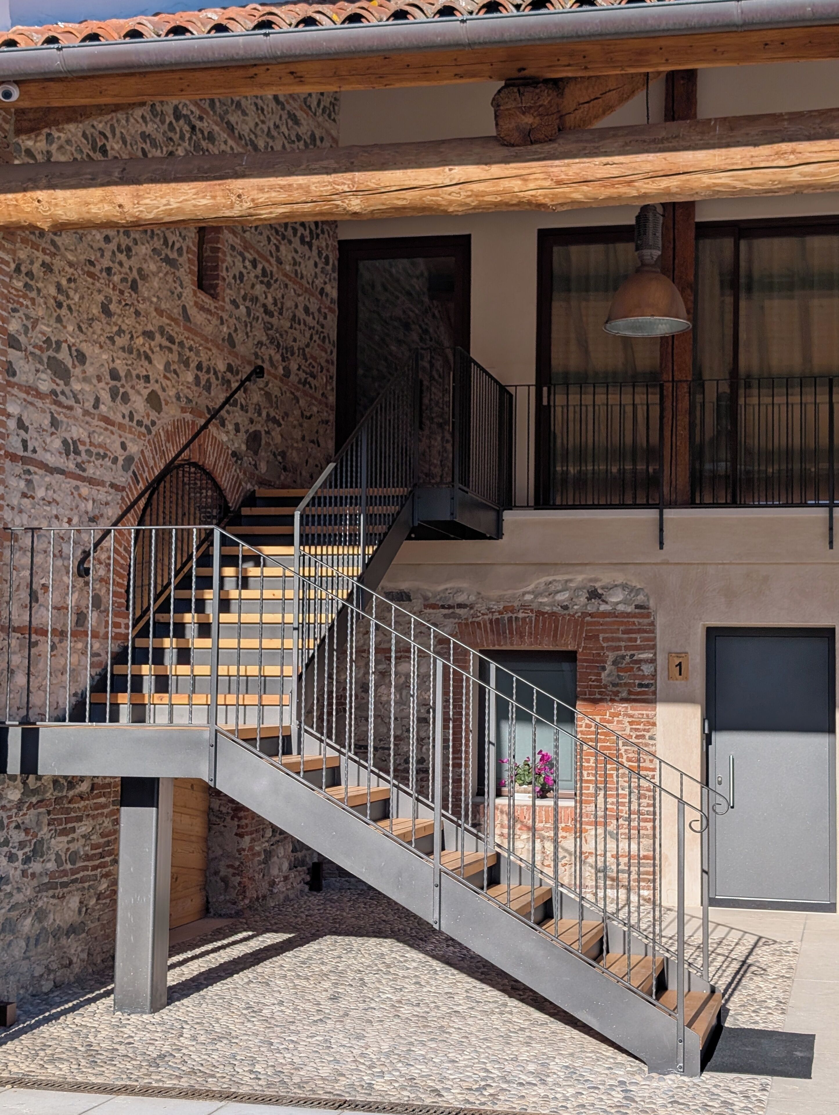 Edificio a più livelli con una scala, pareti in pietra e una porta con il numero 1.