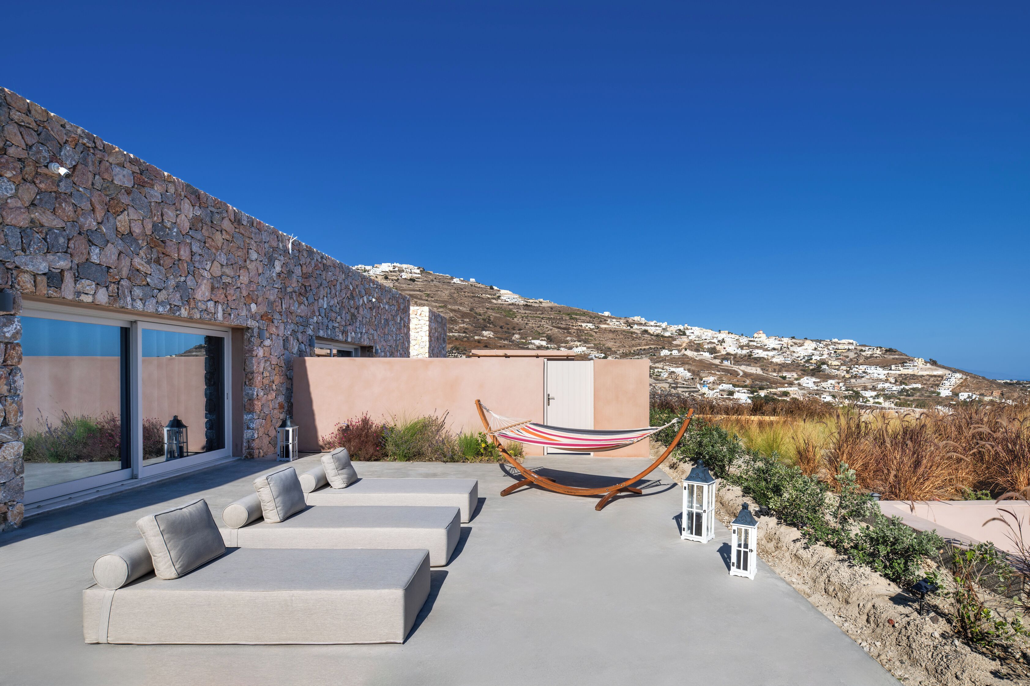 A modern outdoor seating area with lounge chairs and a hammock, overlooking a scenic hillside.