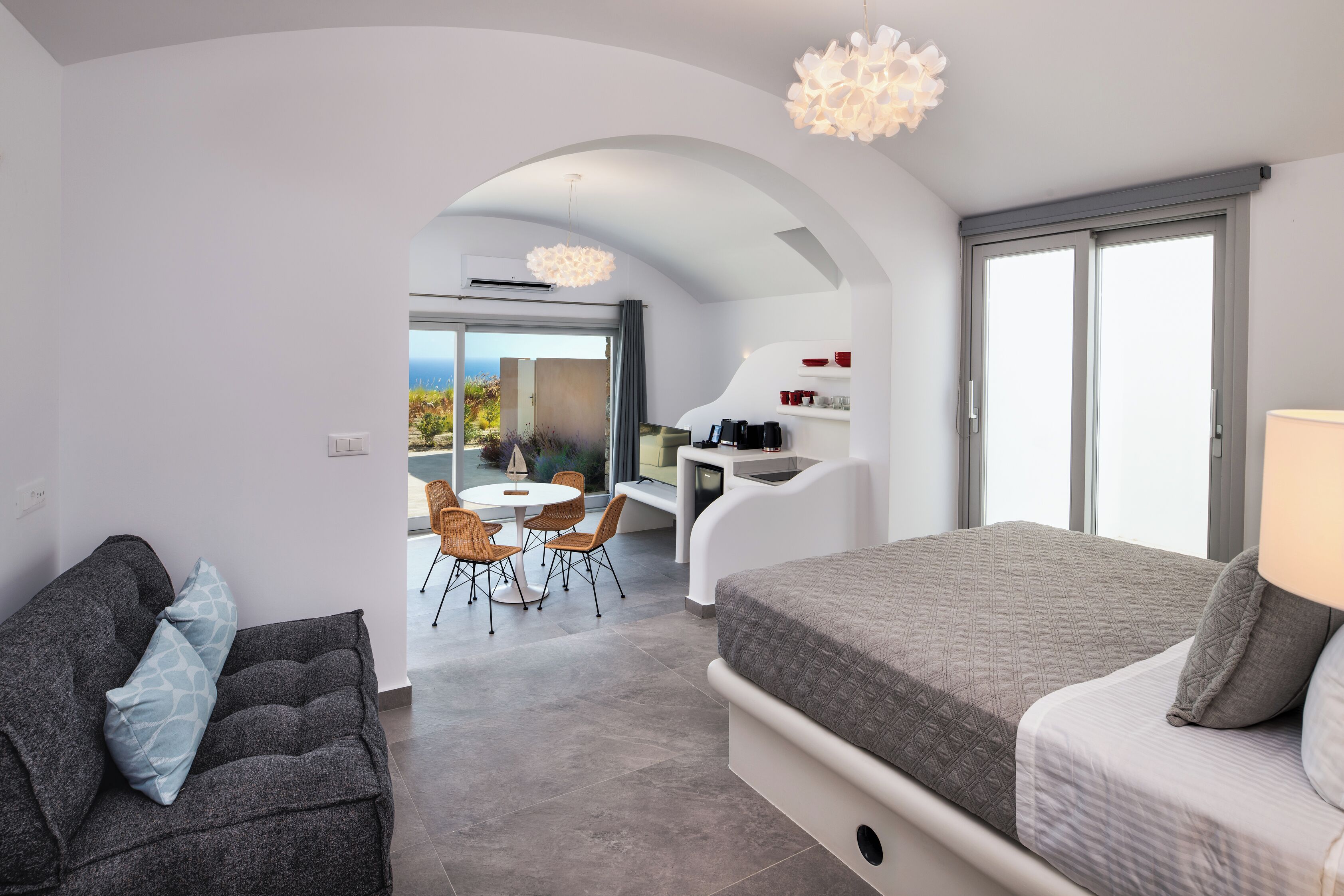 Une chambre moderne avec un grand lit, un canapé et un coin repas avec des chaises.