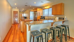 A modern kitchen with a central island, bar stools, wooden cabinets, and built-in appliances. - Hot Tub with Amazing Views, Game Room, Family Friendly, Central Location (Glenwood Springs)