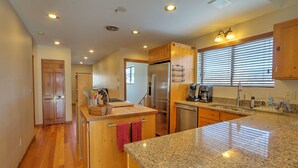 A modern kitchen with wooden cabinets, granite countertops, stainless steel appliances, and a window with blinds. - Hot Tub with Amazing Views, Game Room, Family Friendly, Central Location (Glenwood Springs)