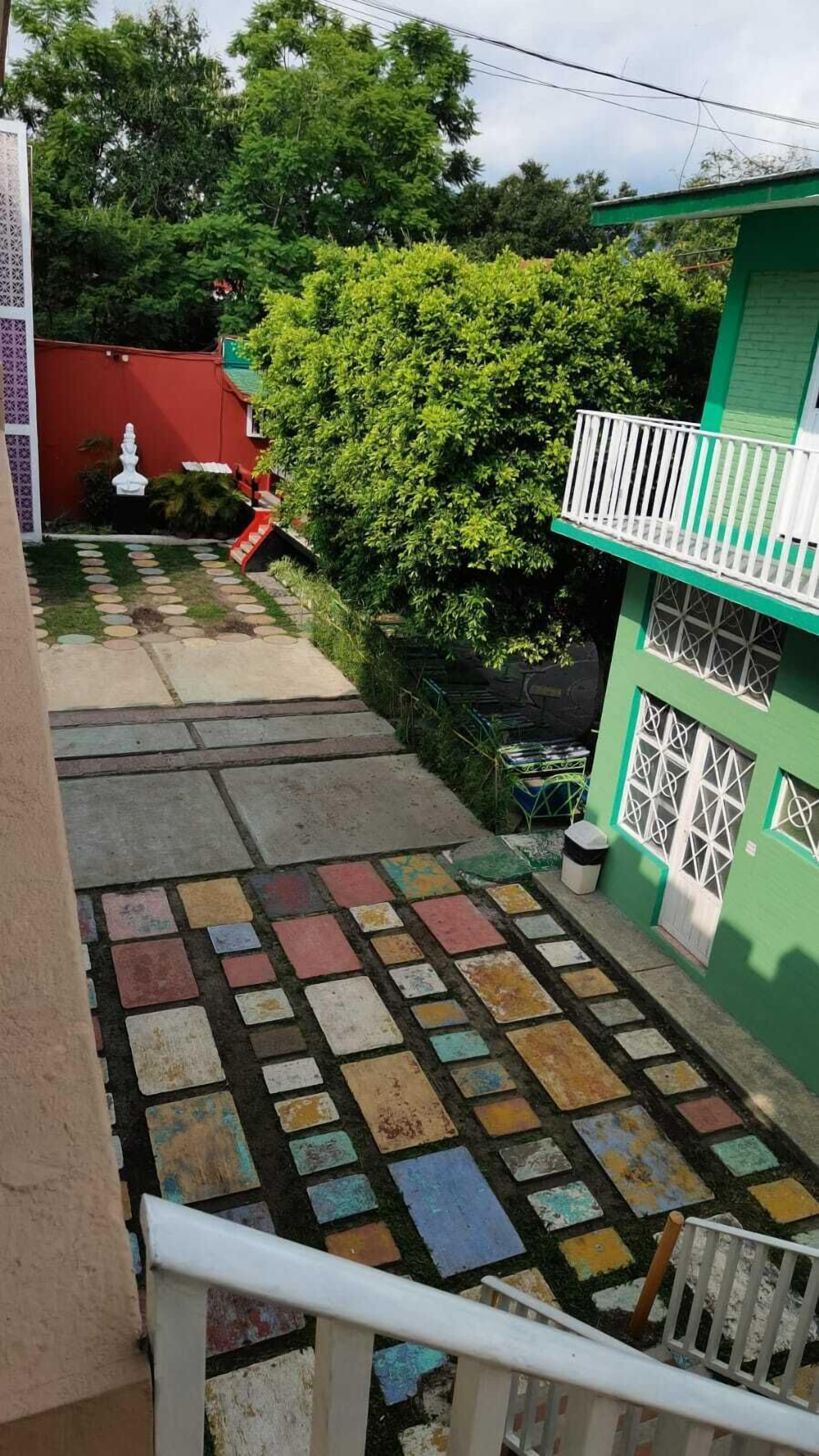Una escala amb rajoles de colors que condueix a un edifici verd amb baranes blanques.