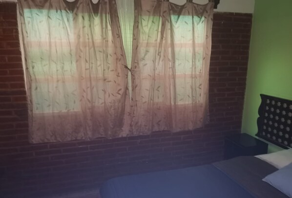 A room with a bed, a window with sheer curtains, a brick wall, and a green wall. - Hotel internacional Cuautla (Cuautla)