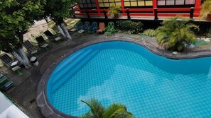 A curved swimming pool with a checkered pattern, surrounded by lounge chairs and potted plants. - Hotel internacional Cuautla (Cuautla)