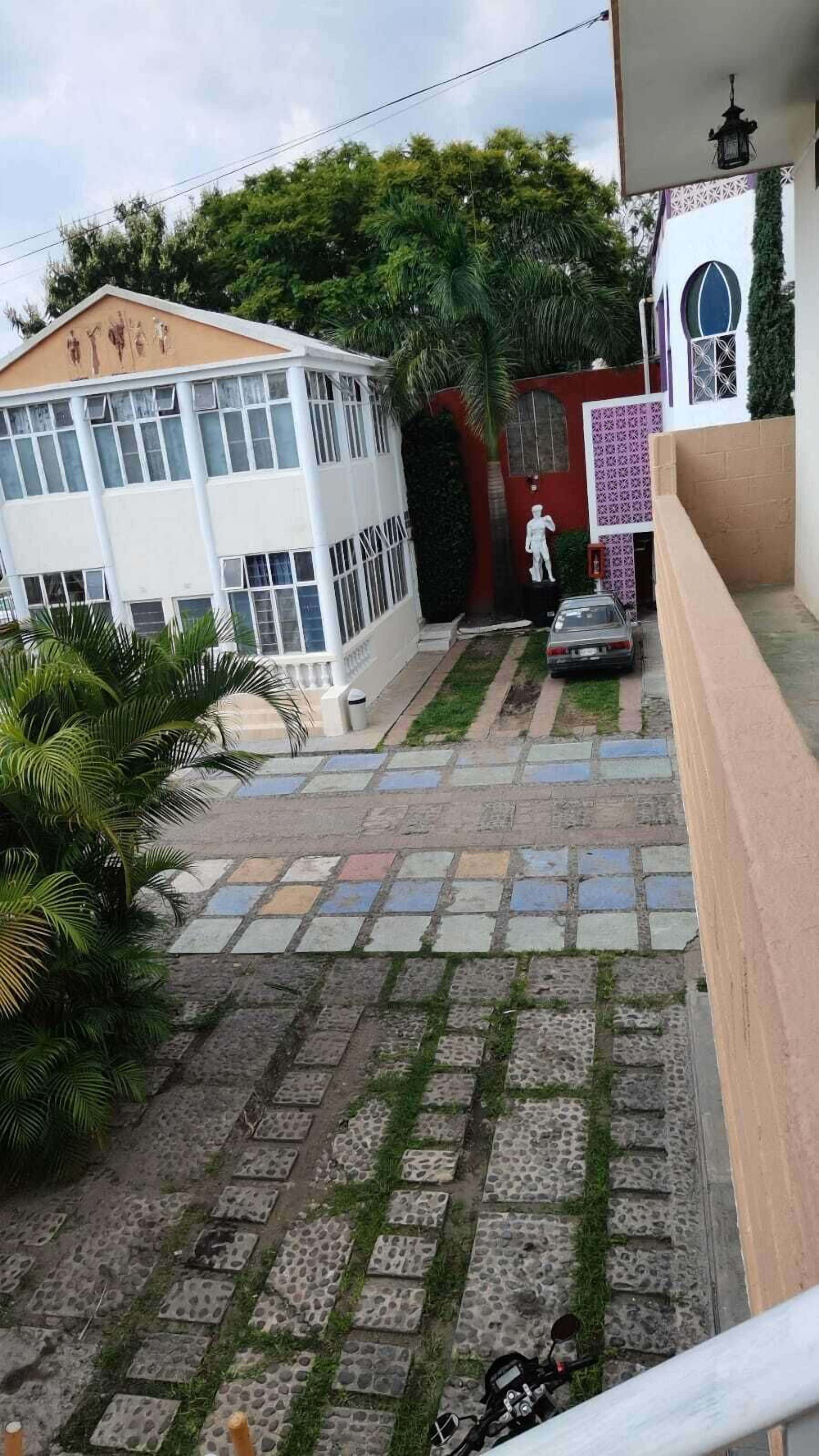 Un edificio con fachada blanca, un coche aparcado delante y una motocicleta en el suelo.