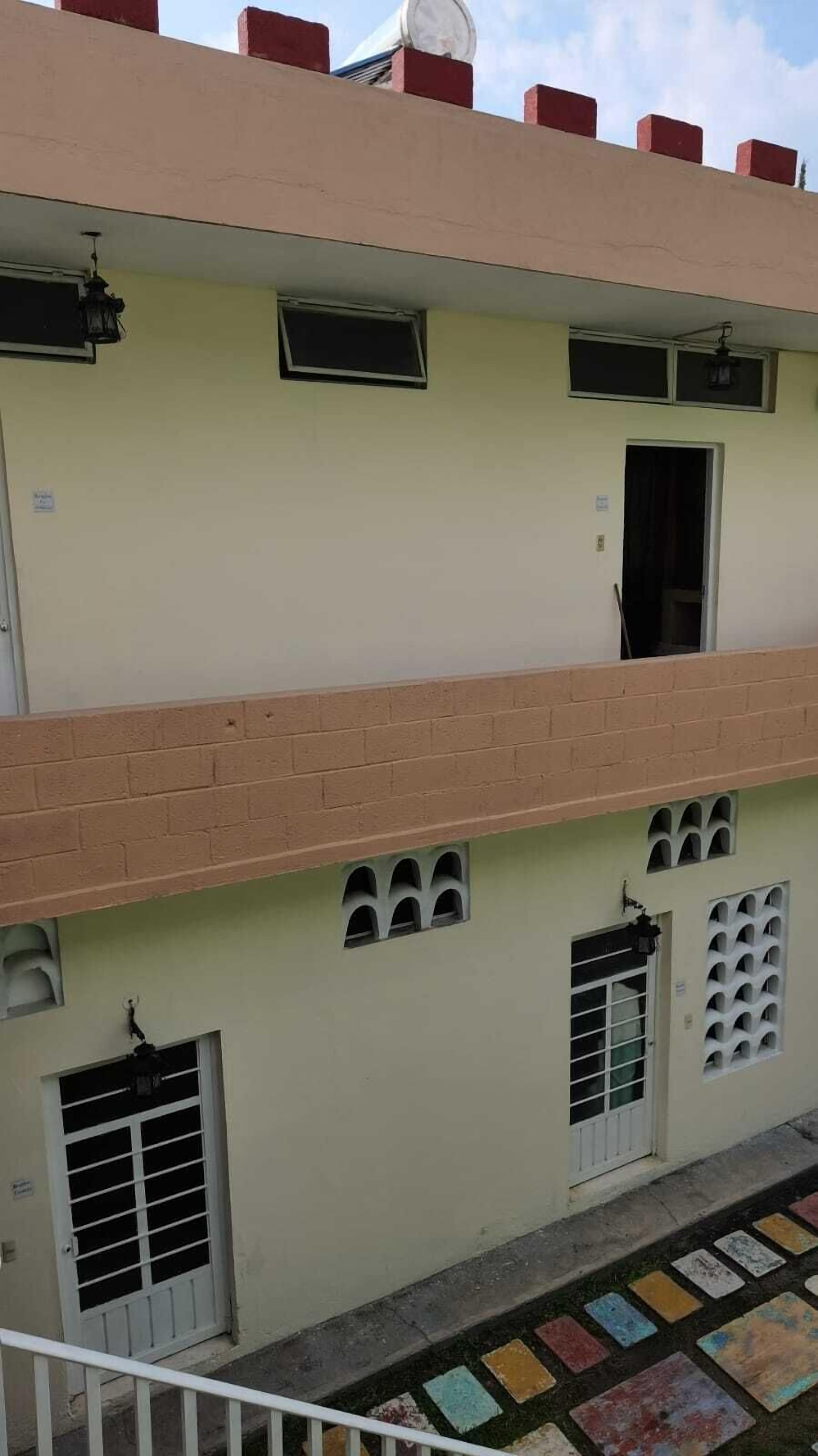 A two-story building with a flat roof, multiple windows, and a balcony.