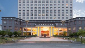 Un hotel de varios pisos con una entrada destacada, un césped bien cuidado y una amplia fachada.
