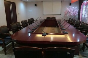 Ett konferensrum med ett långt bord, stolar och en projektorduk.