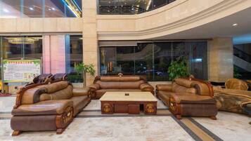A spacious lobby with a large seating area, a central coffee table, and a view of the surrounding area.