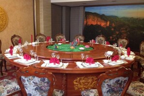 A round table with floral centerpieces and white napkins, surrounded by upholstered chairs with floral patterns. - Gan Jiang Yuan International Hotel (Shicheng)