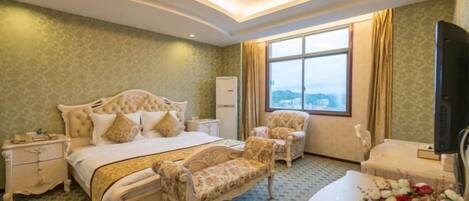 Habitación de hotel con cama, una silla, un escritorio, televisor y ventana con vistas.