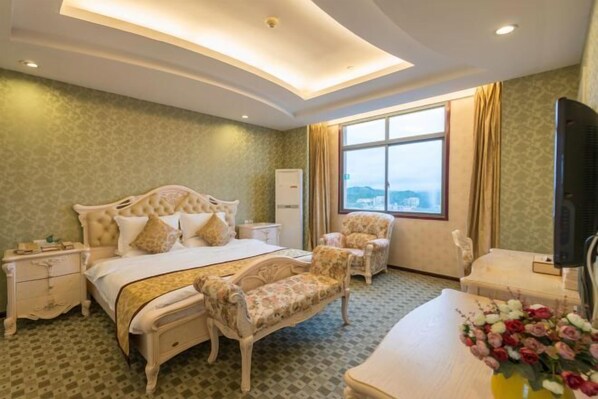 Habitación de hotel con cama, una silla, un escritorio, televisor y ventana con vistas.