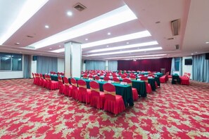 A large conference room with rows of tables and chairs, a patterned carpet, and a high ceiling with recessed lighting. - Gan Jiang Yuan International Hotel (Shicheng)