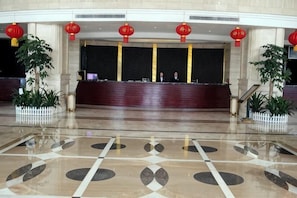 A reception area with a marble floor, reception desk, and red lanterns. - Gan Jiang Yuan International Hotel (Shicheng)