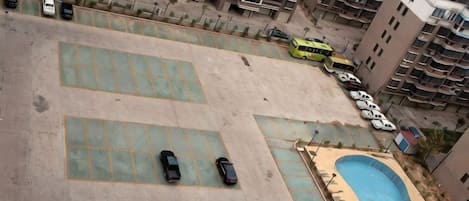A rooftop parking area with multiple cars and a swimming pool.