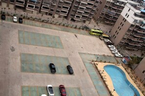 Un aparcamiento en la azotea con varios coches y una piscina.