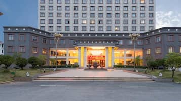 A multi-story hotel with a central entrance, a well-maintained lawn, and a clear sky.