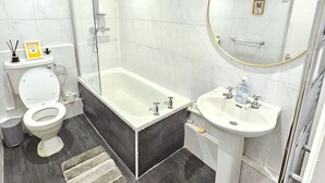 A modern bathroom with a toilet, bathtub, and sink. - Modern 2BR Garden Flat King’s Cross - London (Greater London)