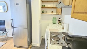 A compact kitchen with a built-in refrigerator, a stove, and wooden cabinets. - Modern 2BR Garden Flat King’s Cross - London (Greater London)