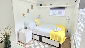 A compact bedroom with a bed, bedside table, and a small desk. - Modern 2BR Garden Flat King’s Cross - London (Greater London)