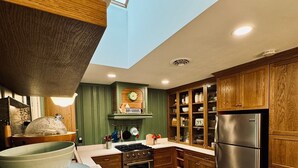 Une cuisine avec des meubles de rangement en bois, un réfrigérateur en acier inoxydable, un carrelage à carreaux et une lucarne.