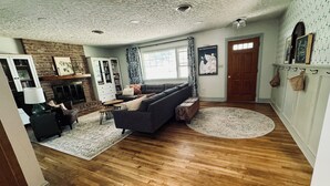 Un salon spacieux avec une cheminée, un ensemble de canapés, une table basse et un tapis.