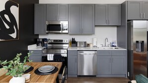 Una cocina moderna con gabinetes grises, electrodomésticos de acero inoxidable y una mesa de comedor de madera.