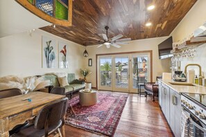 A spacious living area with a wooden ceiling, a dining table, a sofa, and a kitchen with a modern design.