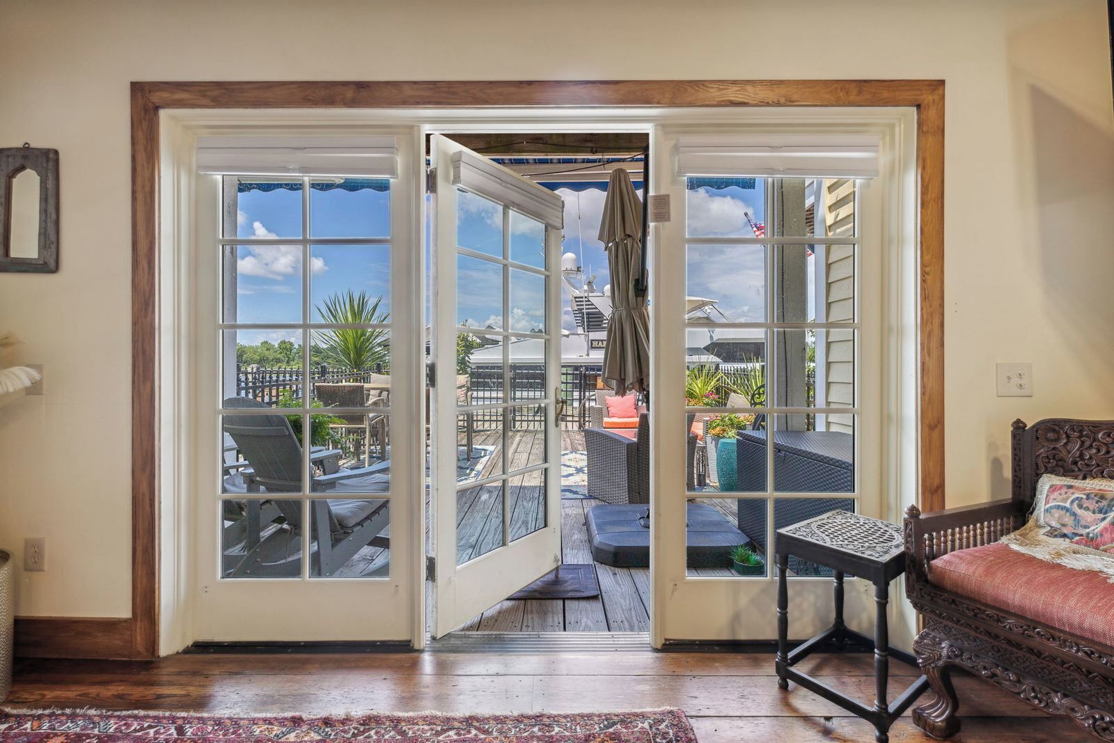 Quarto com porta de vidro deslizante para um pátio externo com mobiliário e vista do céu.