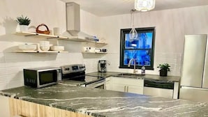 A modern kitchen with a marble countertop, white cabinetry, and a built-in oven. - A Wave From It all - walk to beach - pool! (Holden Beach)