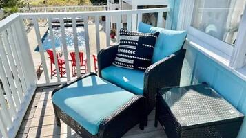 A balcony with a blue cushioned sofa, a small table, and red chairs.