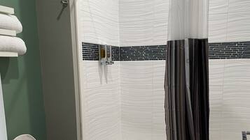 A bathroom with a white toilet, a bathtub, and a shower curtain.