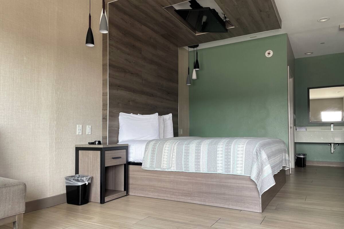 A modern hotel room with a bed, bedside table, and a small trash bin.