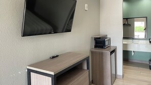 Una cocina moderna con microondas integrado, una pequeña encimera y un televisor de pared.