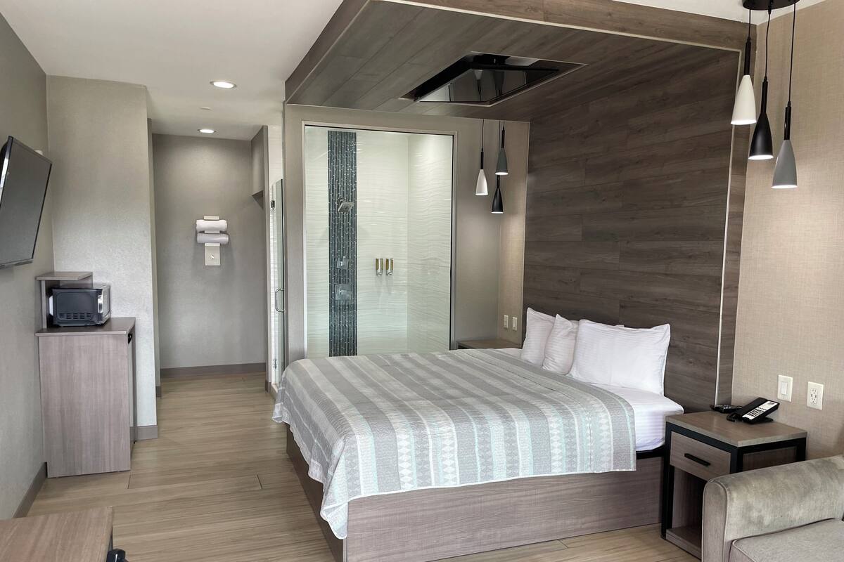 A modern hotel room with a bed, bedside table, and a TV on a cabinet.