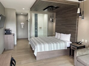 A modern hotel room with a bed, bedside table, and a TV on a cabinet. - Express Inn - Richey (Houston)