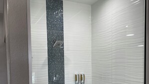 Un baño moderno con ducha, separador de vidrio y pared de azulejos.