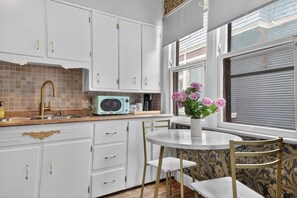 Una cocina con armarios blancos, una radio antigua y un ventanal con vistas.