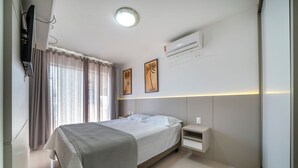 Een moderne hotelkamer met een bed, nachtkastje en een airconditioning aan de muur.