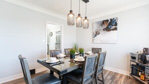 A dining area with a rectangular table, four chairs, and pendant lighting. - Outdoor Sauna|Hot Tub|Playroom|Port Dallhousie (St. Catharines)