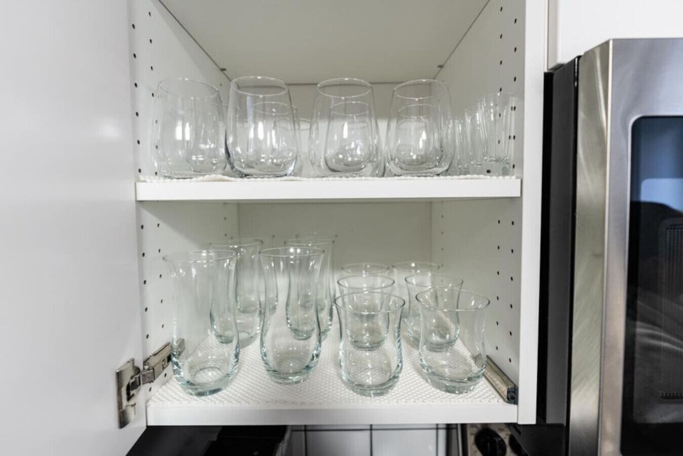 A storage cabinet with multiple shelves holding clear glass tumblers.