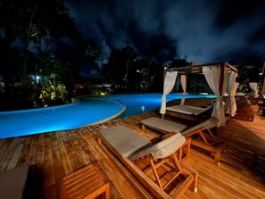Un espace aménagé au bord de la piscine, prévu pour la nuit, avec des chaises longues en bois et une structure en forme de tonnelle.